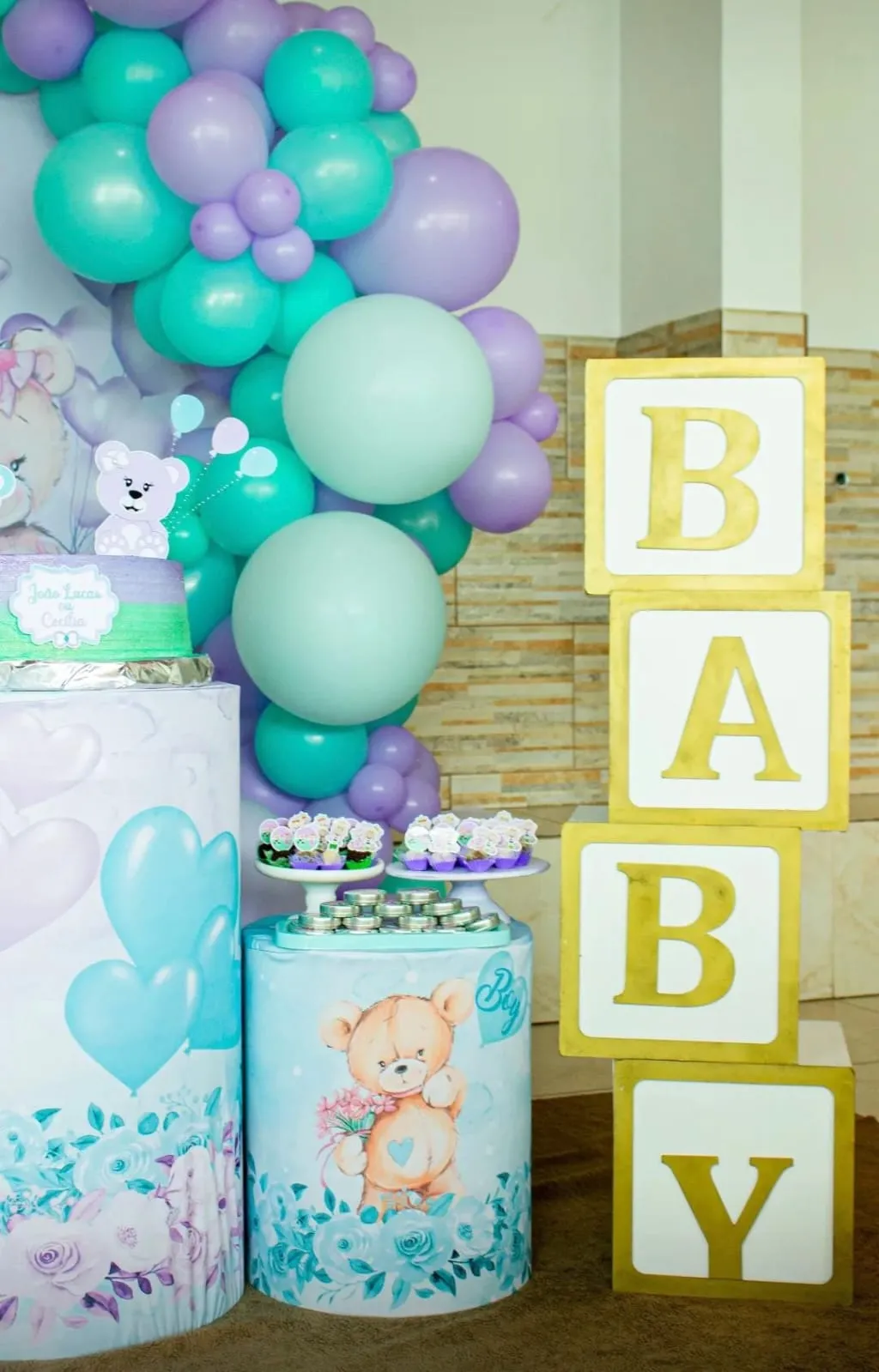 Decoração de chá revelação com balões verde-água e lilás, ursinhos e cubos com a palavra BABY
